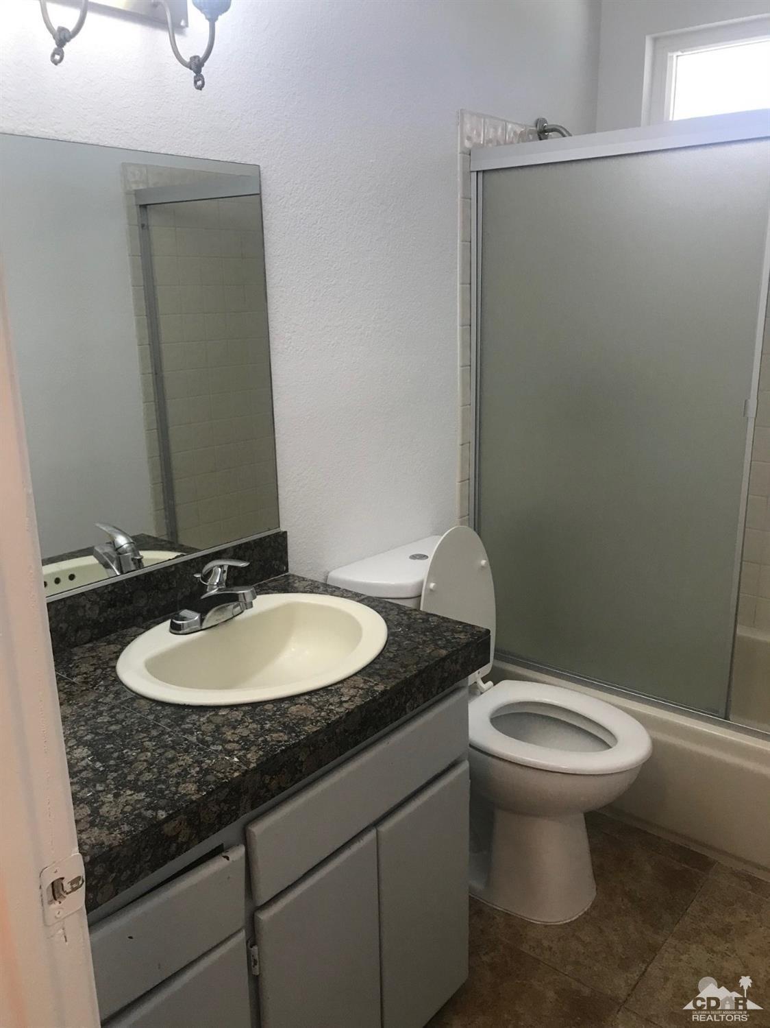 68535 Risueno Road Cathedral City, CA 92234 - Photo 10 of 15 a bathroom with a granite countertop sink toilet and a mirror