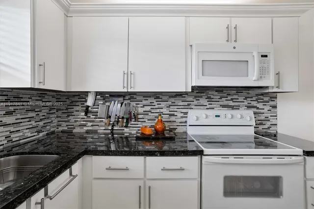 a kitchen with granite countertop white cabinets and white appliances