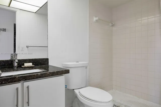 a bathroom with a granite countertop sink toilet and shower