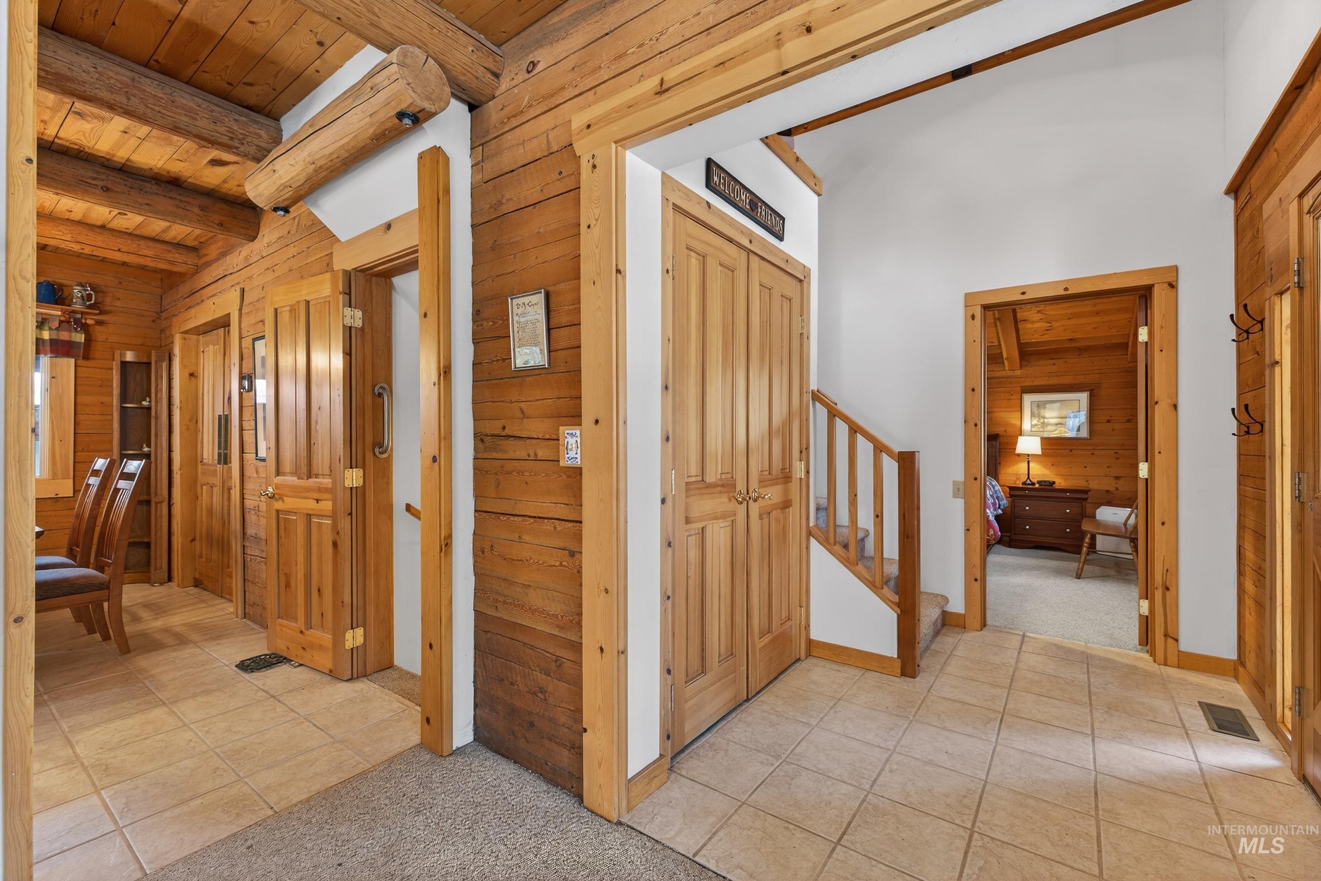 441 Allen Avenue McCall, ID 83638 - Photo 15 of 46 Corridor featuring wooden walls, light carpet, light tile patterned floors, and a wooden ceiling with exposed beams