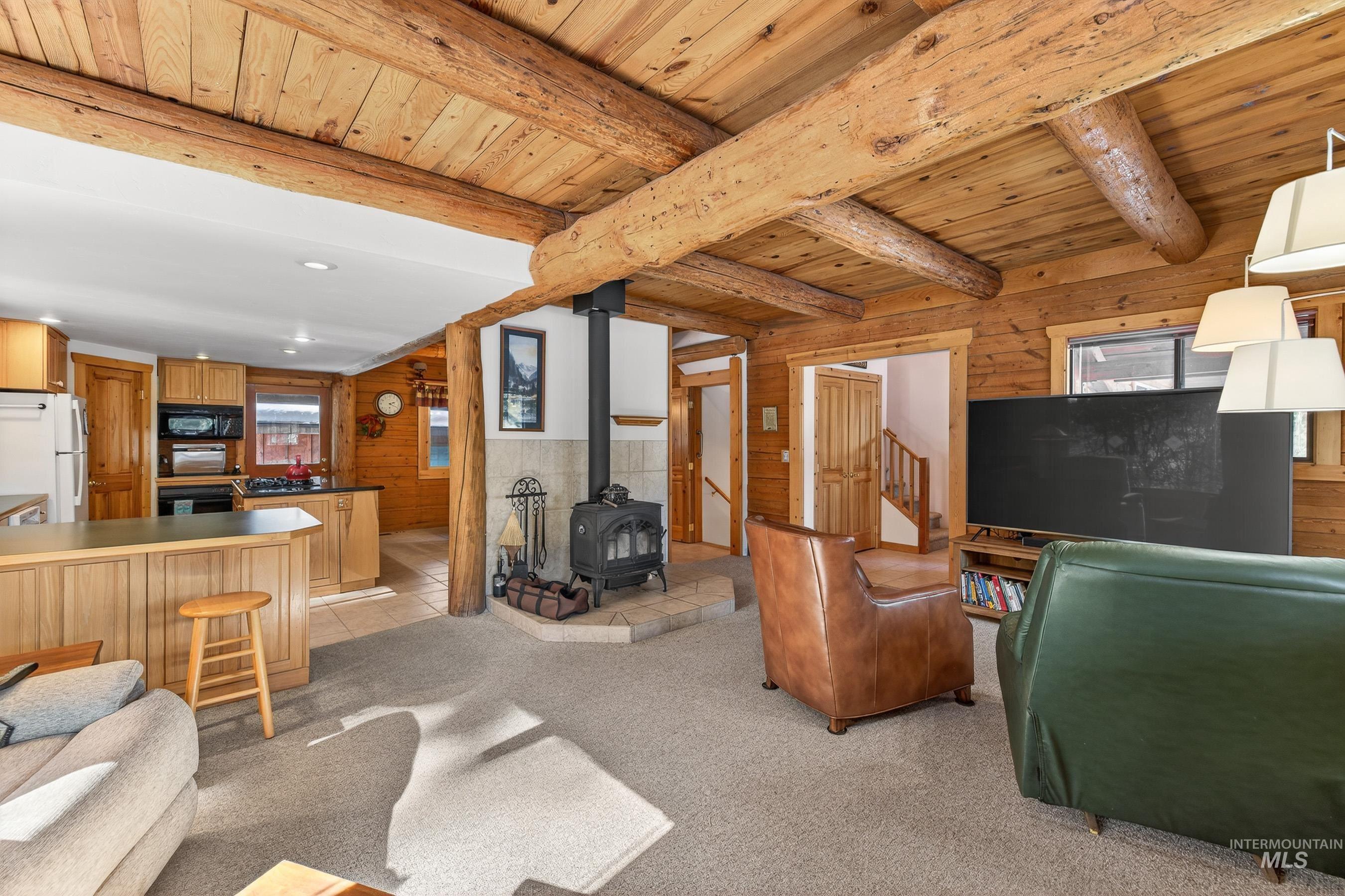 441 Allen Avenue McCall, ID 83638 - Photo 17 of 46 Living room with wooden walls, a wood stove, light carpet, recessed lighting, and a wooden ceiling with exposed beams