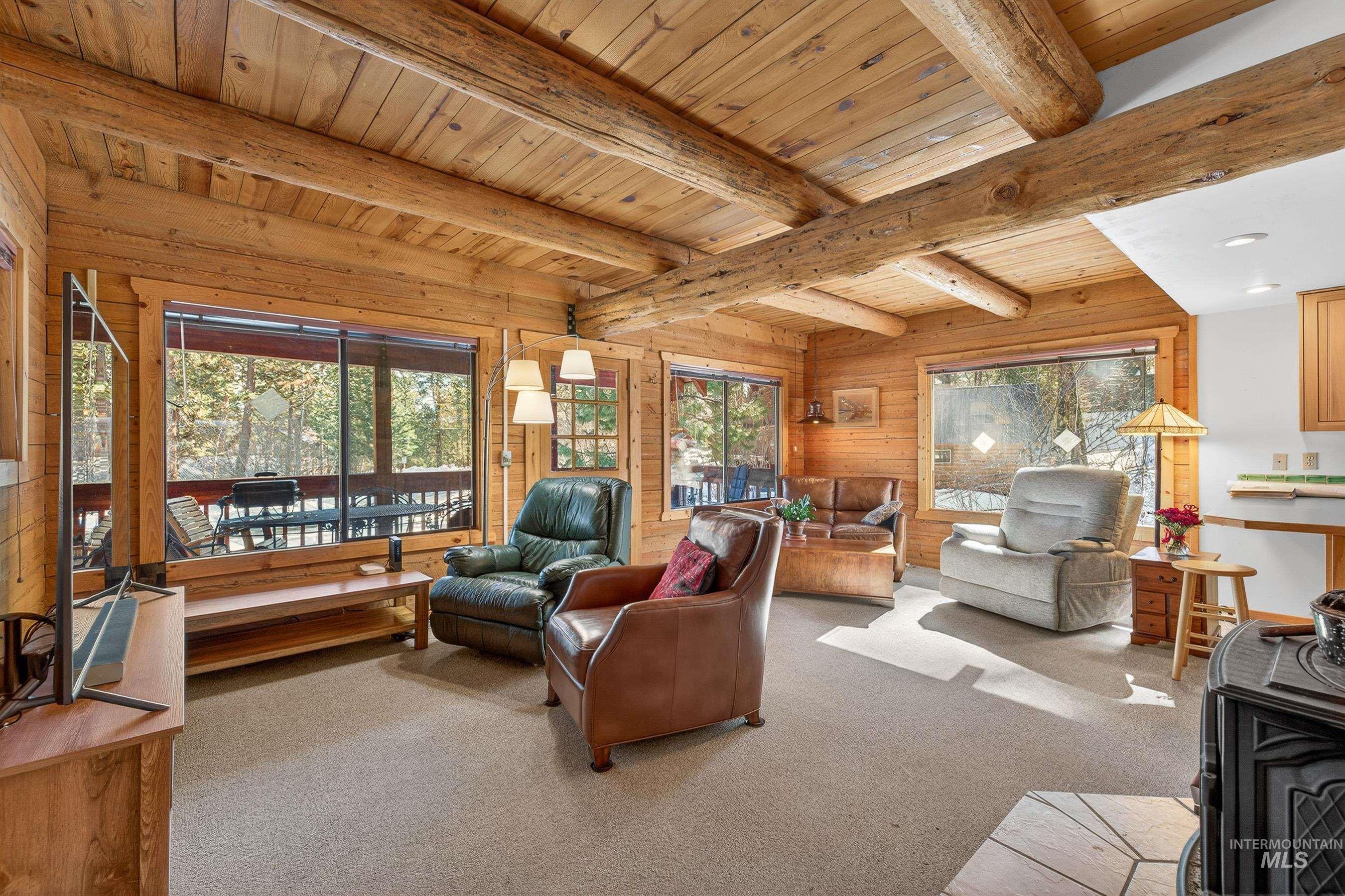 441 Allen Avenue McCall, ID 83638 - Photo 21 of 46 Living area featuring carpet, plenty of natural light, wooden walls, and a wood ceiling with exposed beams