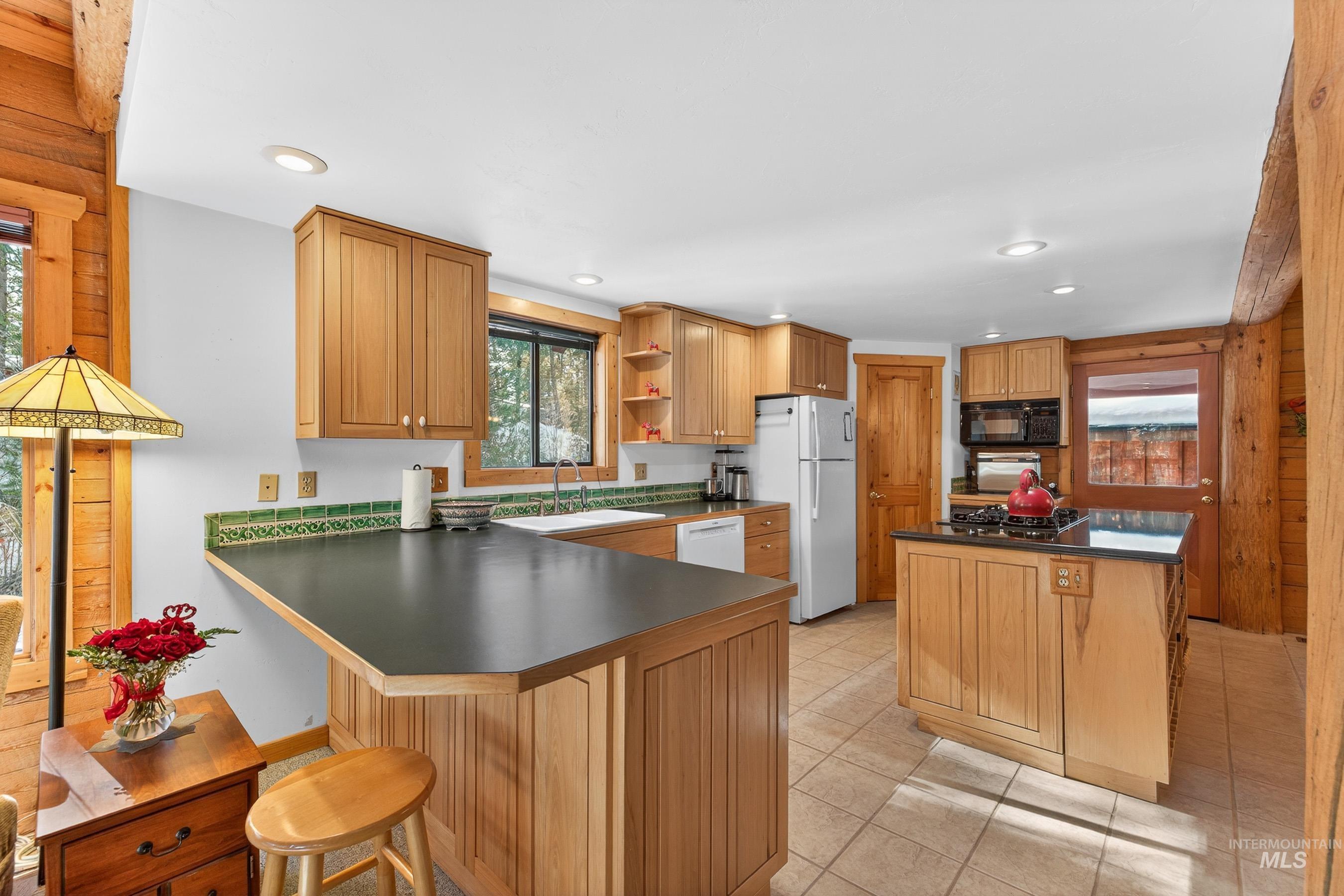 441 Allen Avenue McCall, ID 83638 - Photo 25 of 46 Kitchen featuring dark countertops, a center island, a peninsula, white appliances, and wooden walls