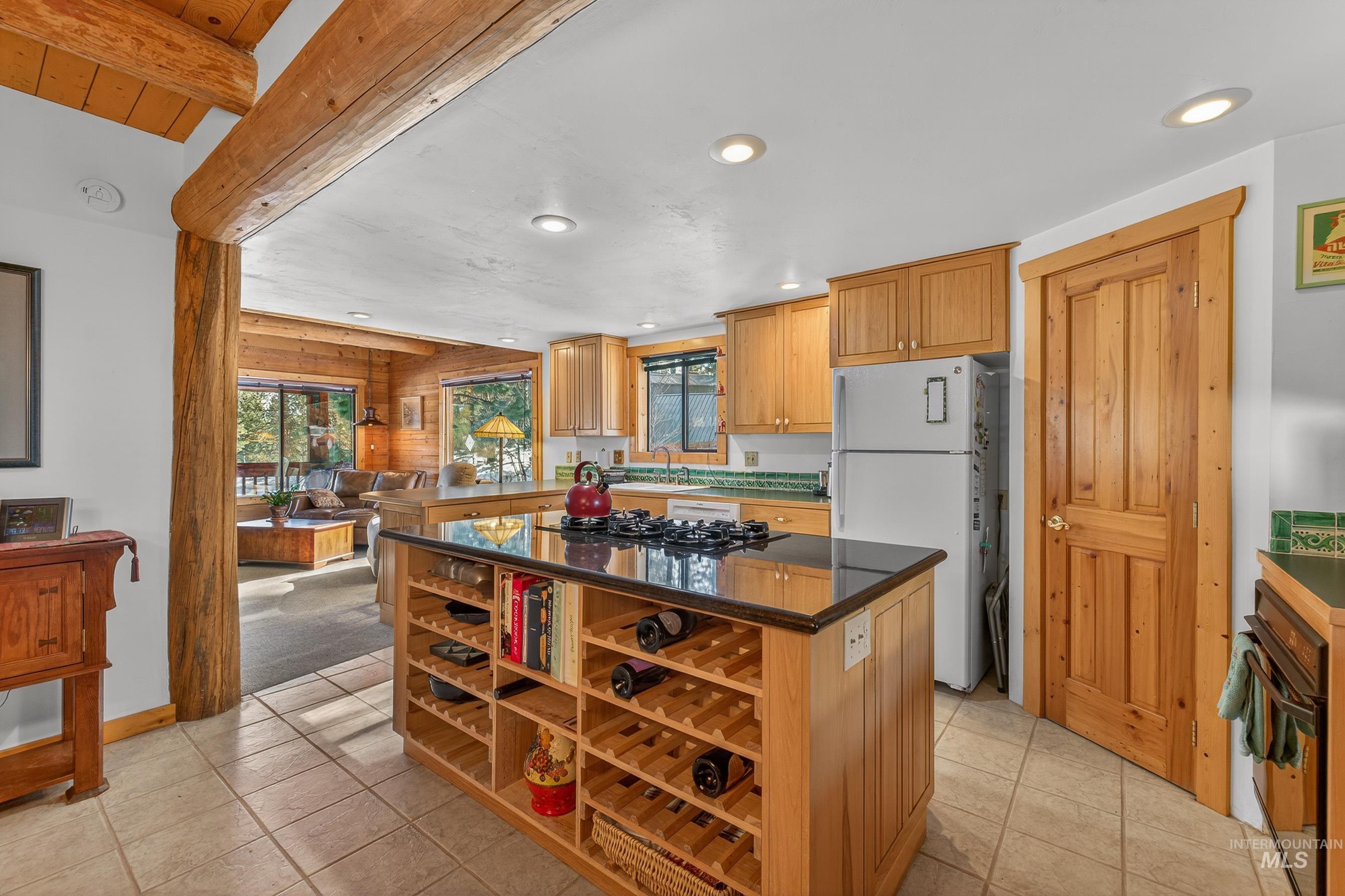 441 Allen Avenue McCall, ID 83638 - Photo 28 of 46 Kitchen with black appliances, a kitchen island, beam ceiling, light tile patterned flooring, and dark stone countertops