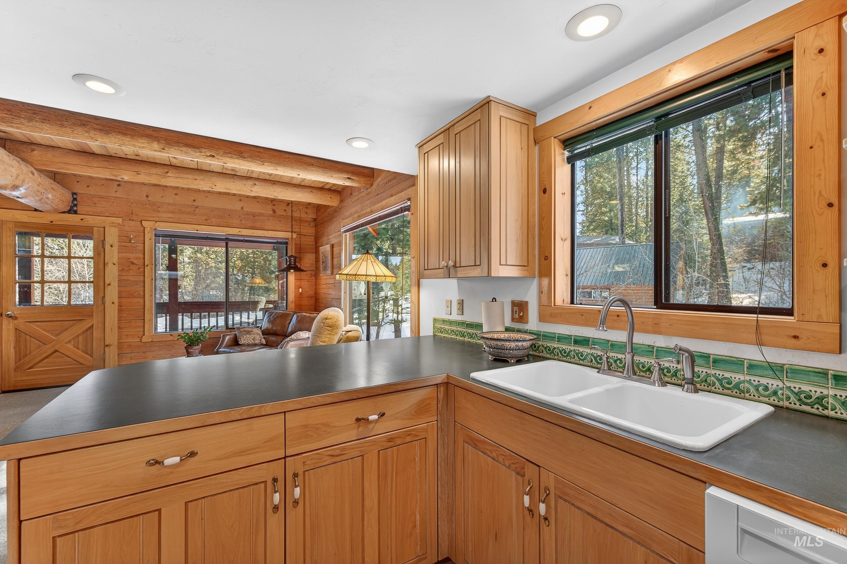 441 Allen Avenue McCall, ID 83638 - Photo 46 of 46 Kitchen featuring dark countertops, a peninsula, beamed ceiling, open floor plan, and wooden walls