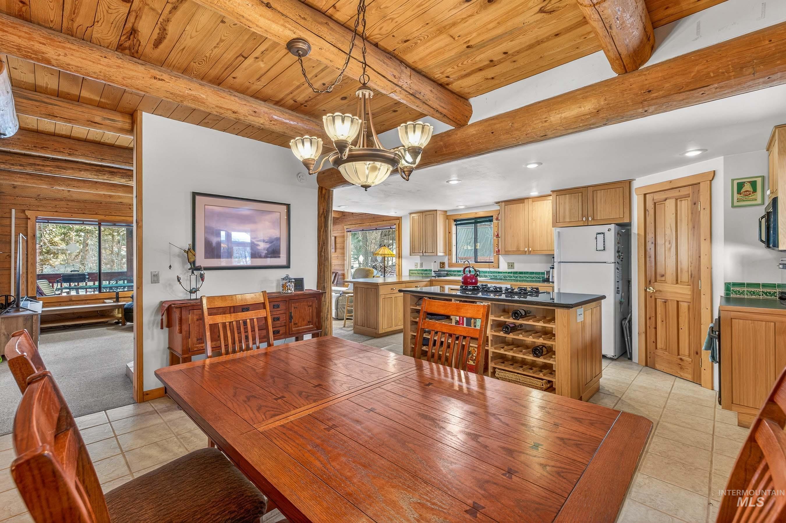 441 Allen Avenue McCall, ID 83638 - Photo 29 of 46 Dining room featuring a chandelier, light tile patterned flooring, and a wooden ceiling with exposed beams