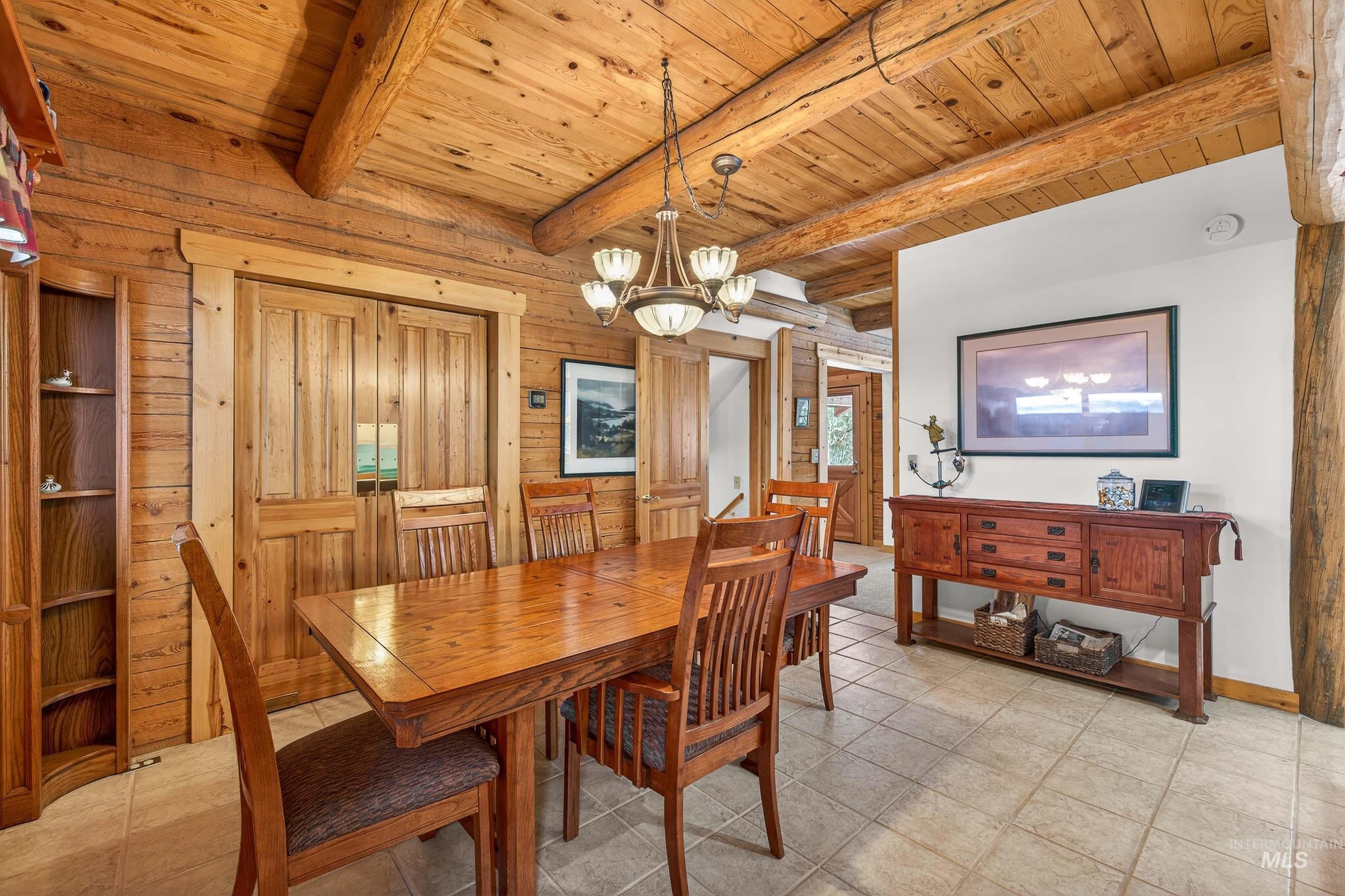 441 Allen Avenue McCall, ID 83638 - Photo 30 of 46 Dining space with hanging lights, a wooden ceiling with exposed beams, wood walls, and light tile patterned flooring