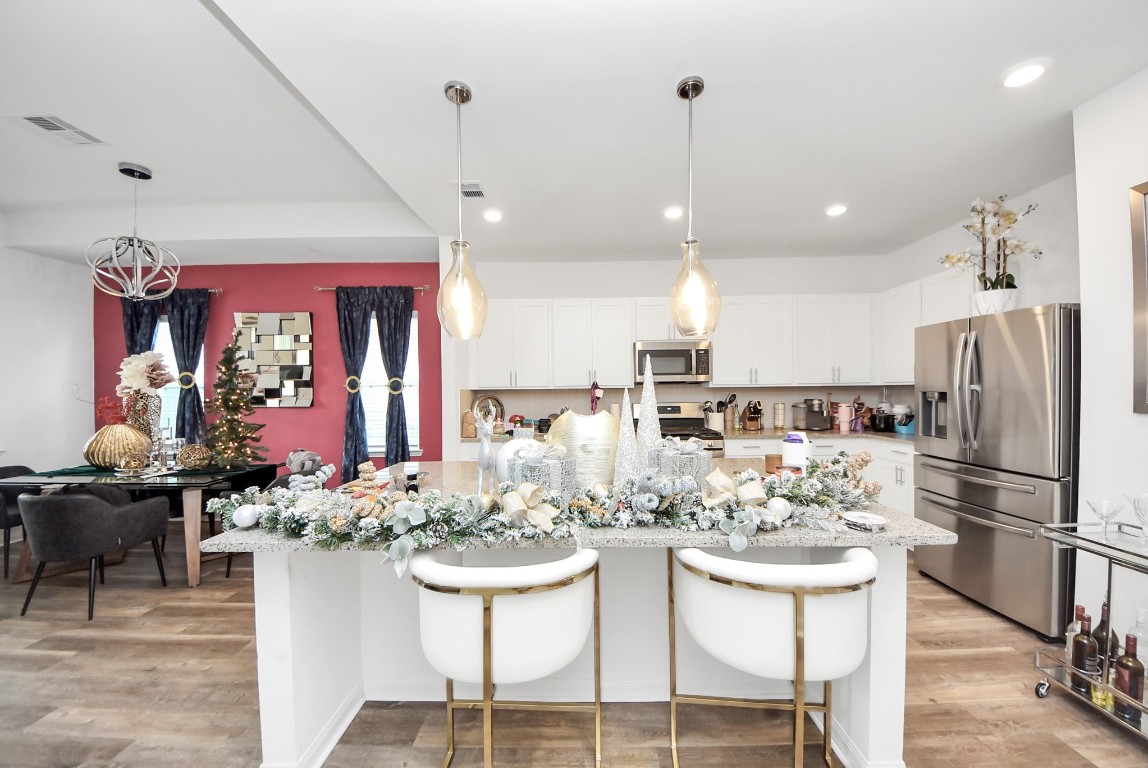 9447 Klein Lane Houston, TX 77044 - Photo 14 of 41 a kitchen with stainless steel appliances kitchen island granite countertop a dining table chairs and white cabinets