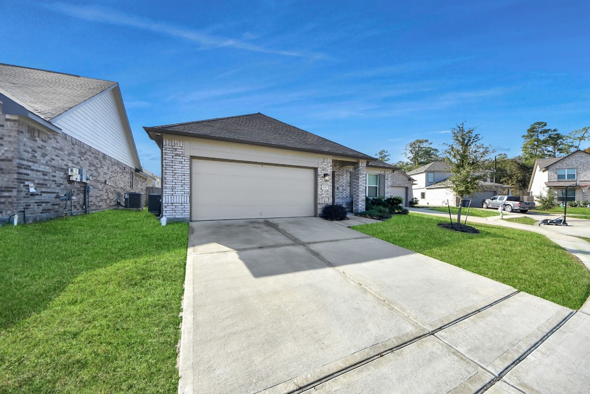 9447 Klein Lane Houston, TX 77044 - Photo 4 of 41 a view of a white house next to a yard with big trees