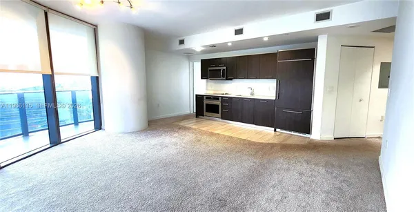 a view of a kitchen with stainless steel appliances wooden floor and a window