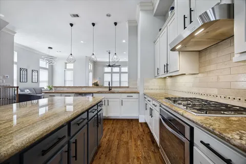 a kitchen with granite countertop a stove a sink dishwasher and cabinets with wooden floor