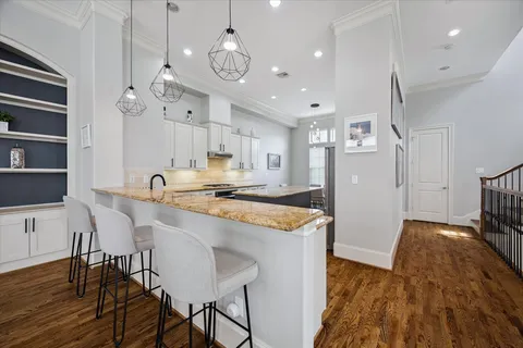 a large kitchen with granite countertop a stove a sink a refrigerator and a dining table