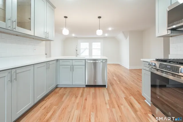 a large kitchen with a wooden floor and stainless steel appliances