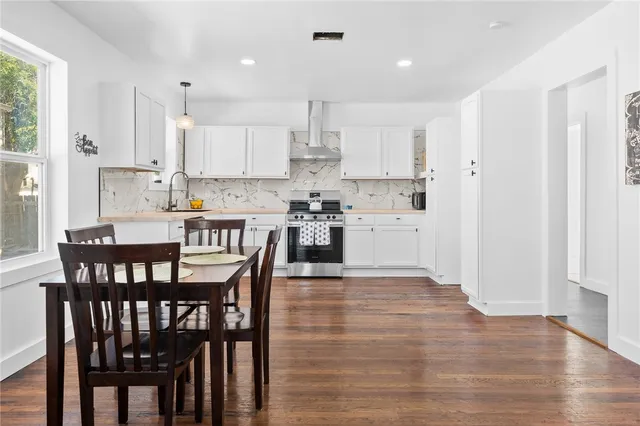 a kitchen with kitchen island granite countertop a dining table chairs and white cabinets