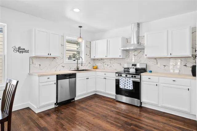 a kitchen with cabinets stainless steel appliances a sink and wooden floor