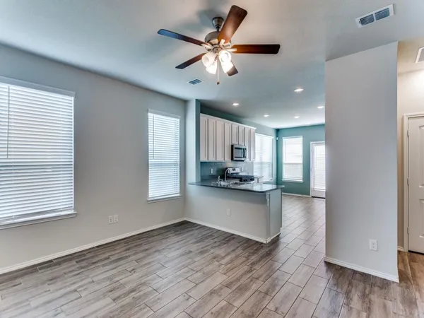 a kitchen with stainless steel appliances kitchen island wooden floors and white cabinets