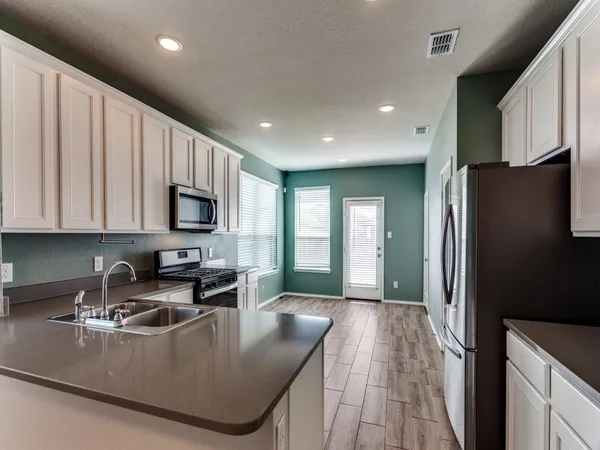 a kitchen with stainless steel appliances granite countertop a sink a stove and a refrigerator