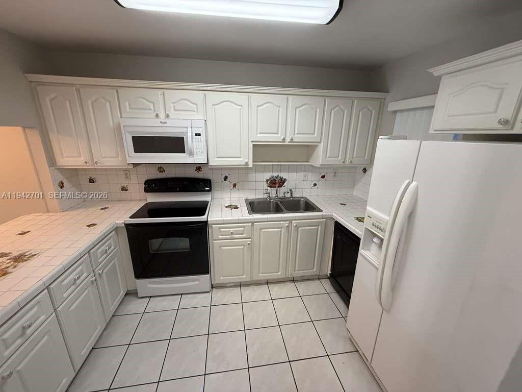 305 West 68th Street, Unit 519 Hialeah, FL 33014 - Photo 2 of 11 a kitchen with white cabinets a sink and white appliances