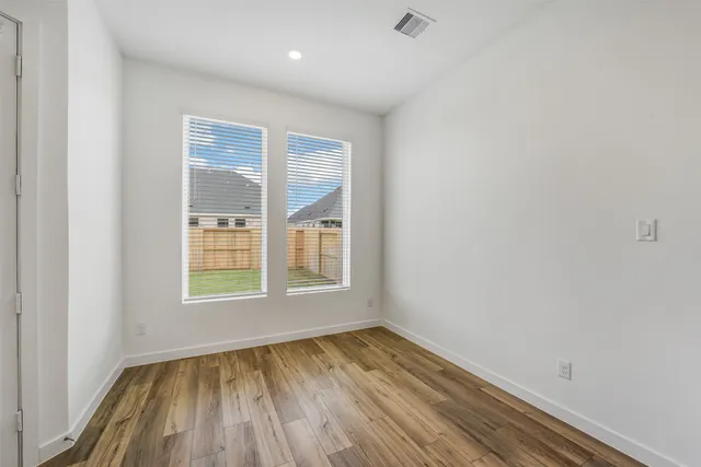an empty room with wooden floor and windows