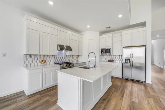 a kitchen with white cabinets and stainless steel appliances