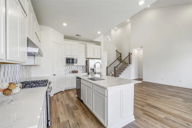 a kitchen with a sink stove and wooden floor