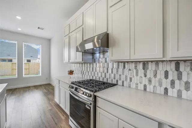a kitchen with granite countertop a stove and white cabinets