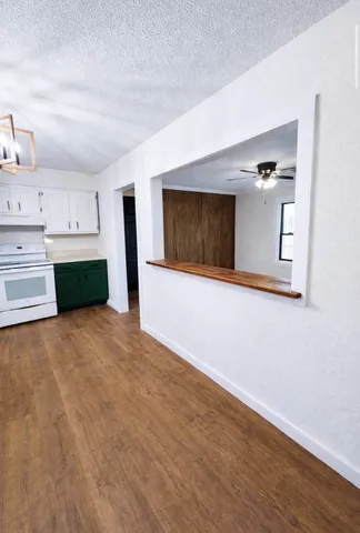 a view of empty room with kitchen and a fireplace