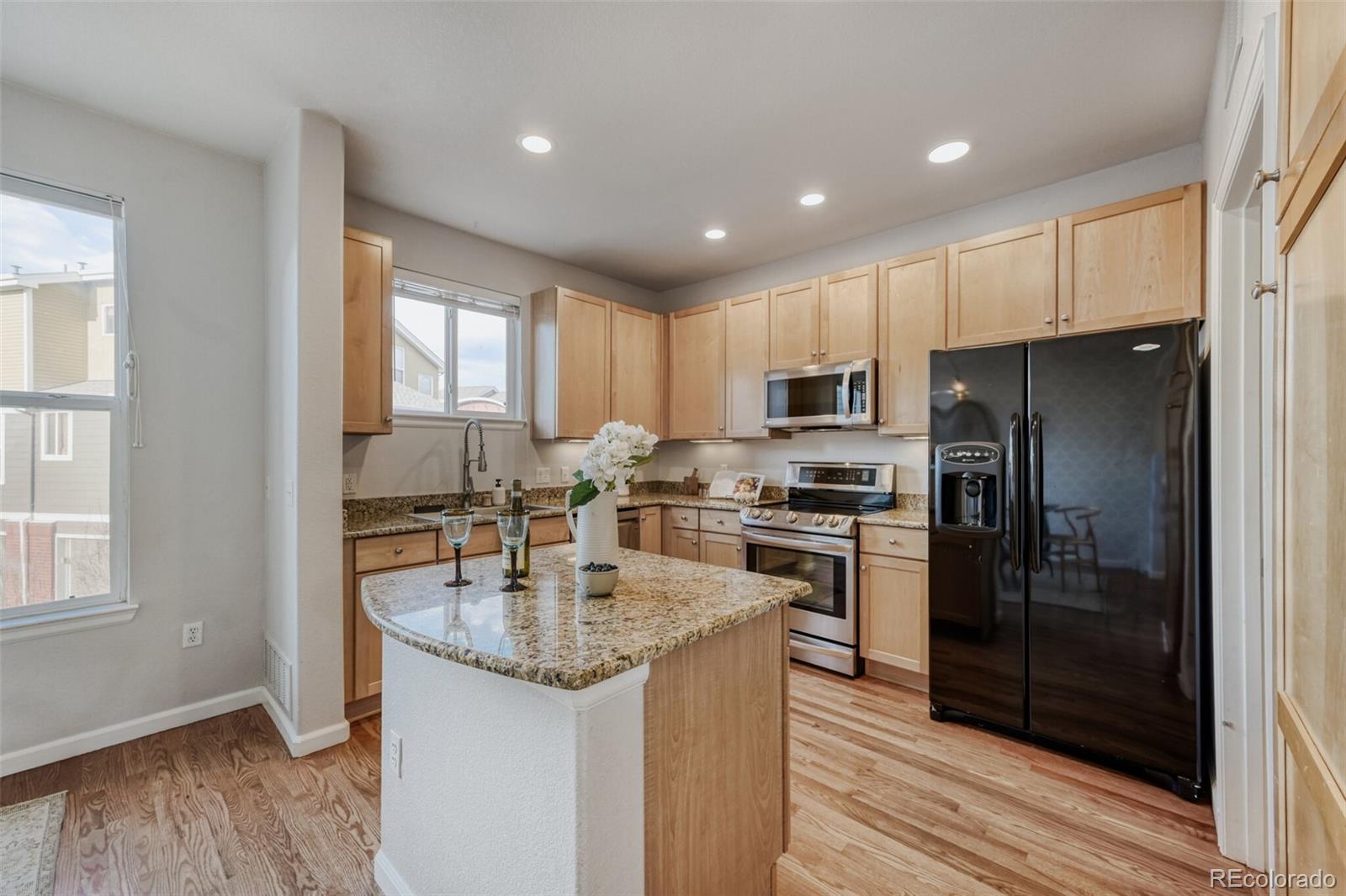 85 Uinta Way, Unit 106 Denver, CO 80230 - Photo 11 of 42 a kitchen with stainless steel appliances granite countertop a refrigerator stove a sink and dishwasher with wooden floor