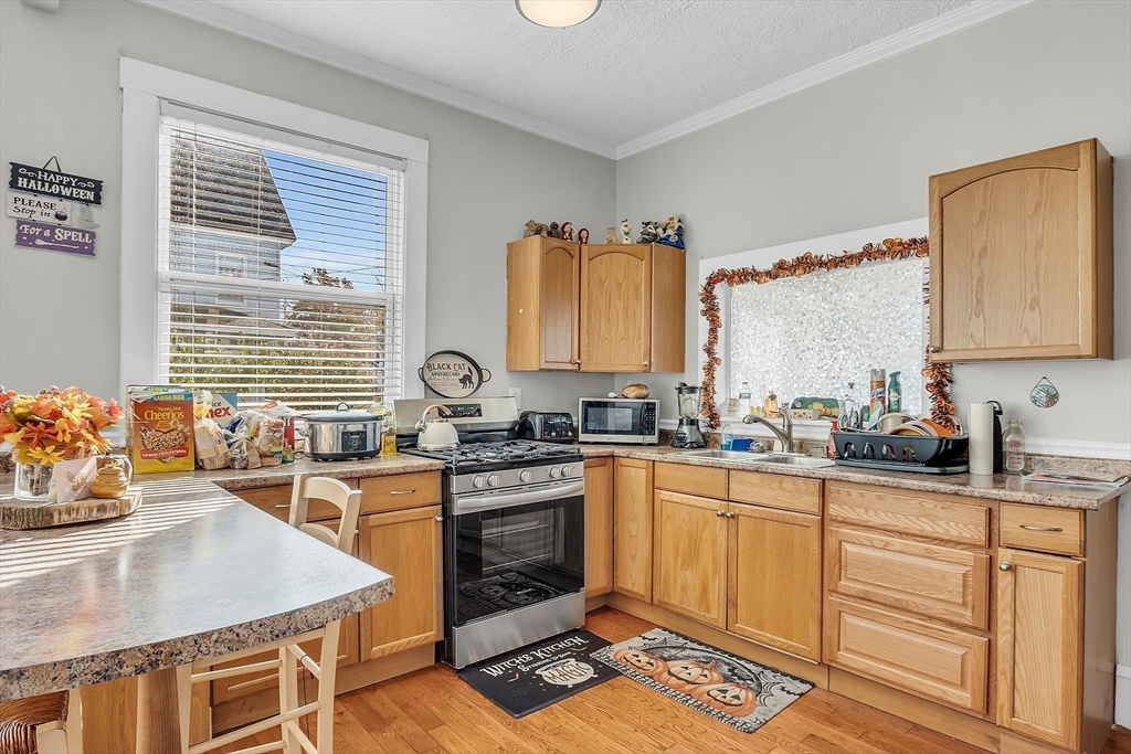 276 Pine Street Lowell, MA 01851 - Photo 9 of 42 a kitchen with stainless steel appliances granite countertop a stove a sink dishwasher and a microwave oven with white cabinets