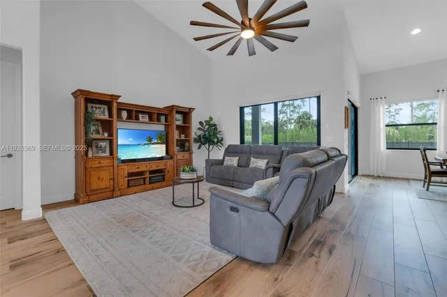 a kitchen with stainless steel appliances kitchen island granite countertop a dining table chairs and white cabinets