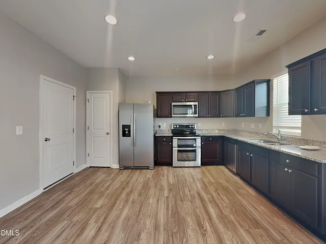 a kitchen with stainless steel appliances granite countertop a refrigerator and a stove top oven