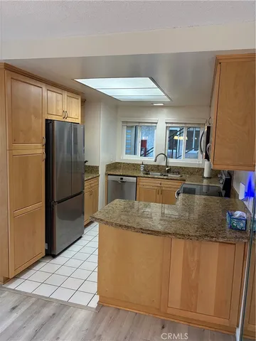 a kitchen with stainless steel appliances granite countertop a refrigerator a stove and a sink with wooden floors