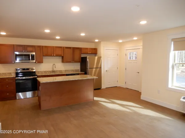 a kitchen with stainless steel appliances granite countertop a refrigerator a stove a sink a microwave a refrigerator and white cabinets with wooden floor
