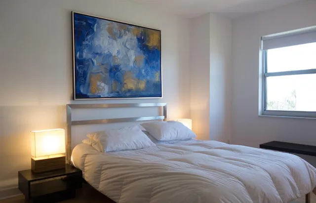 a bedroom with a bed and a painting on the wall