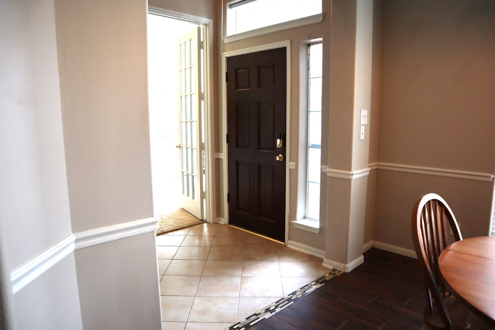 19114 Emory Trail Spring, TX 77388 - Photo 4 of 32 The photo features a welcoming entryway with a dark wood front door and sidelights, providing natural light. The space has a mix of tile and wood flooring, with a small dining area visible, creating an inviting atmosphere.