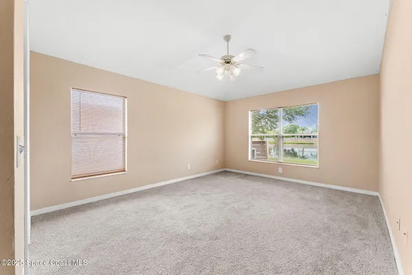 an empty room with chandelier fan and windows