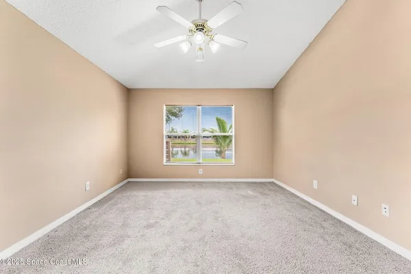 an empty room with windows and fan
