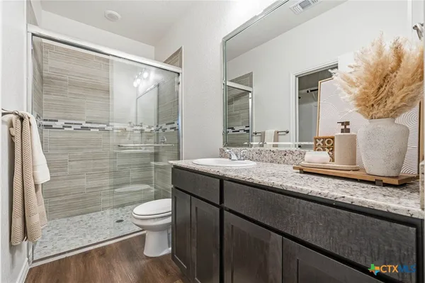 a bathroom with a granite countertop sink a toilet a mirror and shower