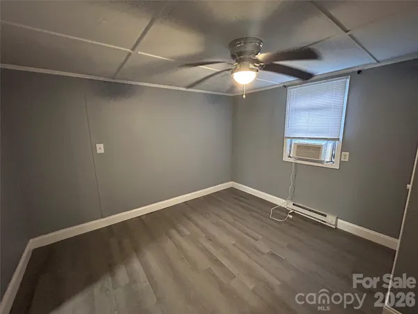 an empty room with chandelier fan and windows