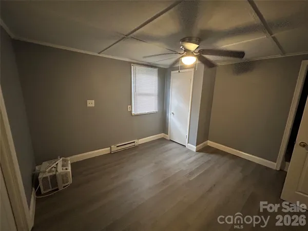 a view of an empty room with window and chandelier fan
