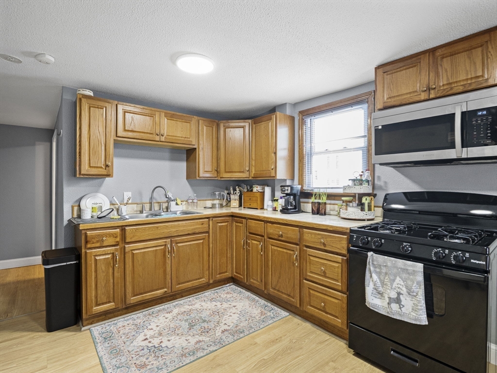 8 Clarks Court Lowell, MA 01852 - Photo 13 of 33 a kitchen with stainless steel appliances granite countertop a stove a sink and a microwave
