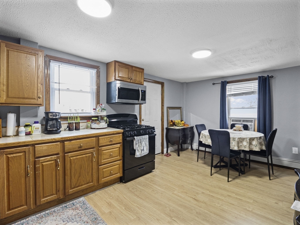 8 Clarks Court Lowell, MA 01852 - Photo 14 of 33 a kitchen with stainless steel appliances granite countertop a stove top oven a sink dishwasher a dining table and chairs with wooden floor