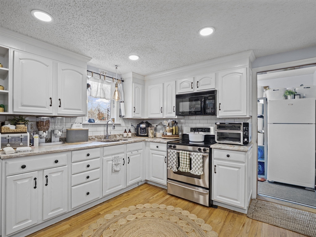 8 Clarks Court Lowell, MA 01852 - Photo 5 of 33 a kitchen with granite countertop white cabinets and stainless steel appliances