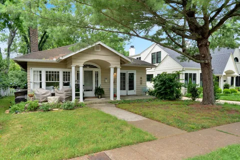 a front view of a house with a garden and trees