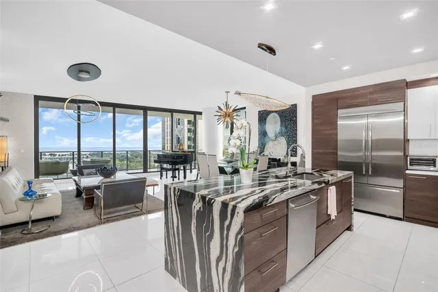 a view of a kitchen with kitchen island a large window a sink and a counter space