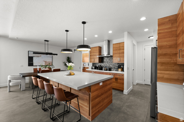 507 West Windmill Gate Cove Draper, UT 84020 - Photo 13 of 46 Kitchen featuring modern cabinets, wood finish cabinetry, a center island, hanging light fixtures, and decorative backsplash