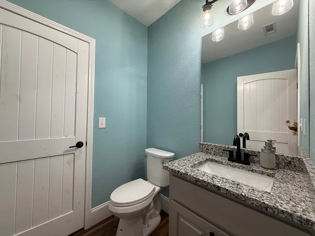 a bathroom with a granite countertop sink a toilet and a mirror