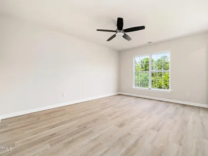 an empty room with wooden floor fan and windows
