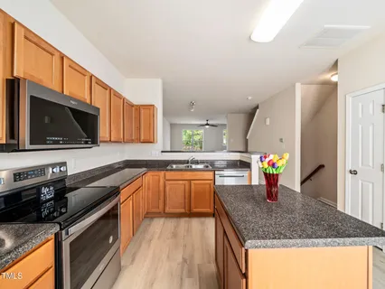 a kitchen with stainless steel appliances granite countertop a sink a stove top oven a counter space and cabinets