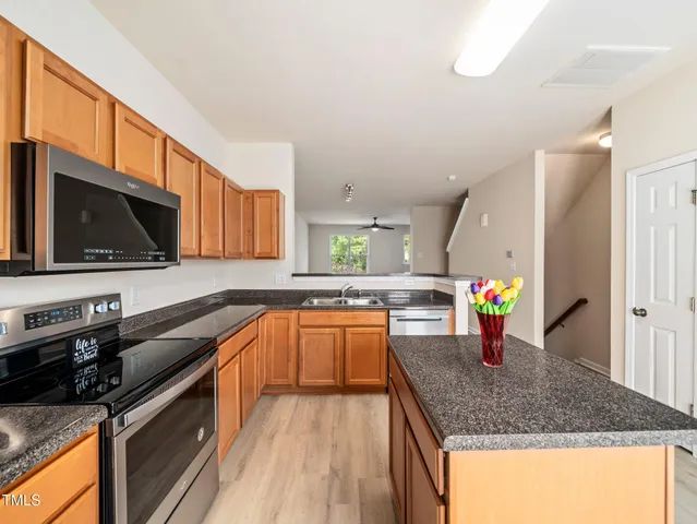 a kitchen with stainless steel appliances granite countertop a sink a stove top oven a counter space and cabinets